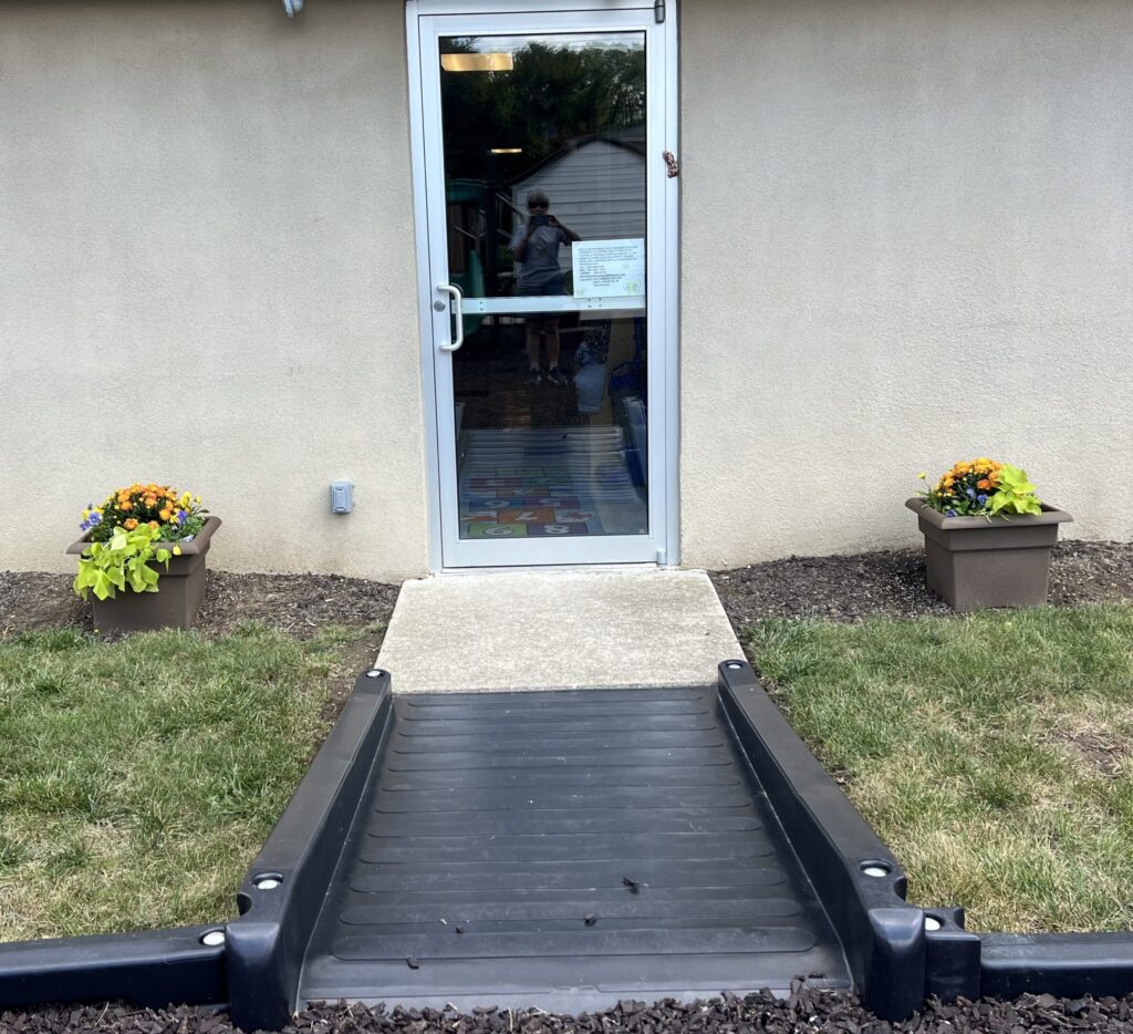 A photograph taken by the door leading to the playground. It showcases two planters of flowers.